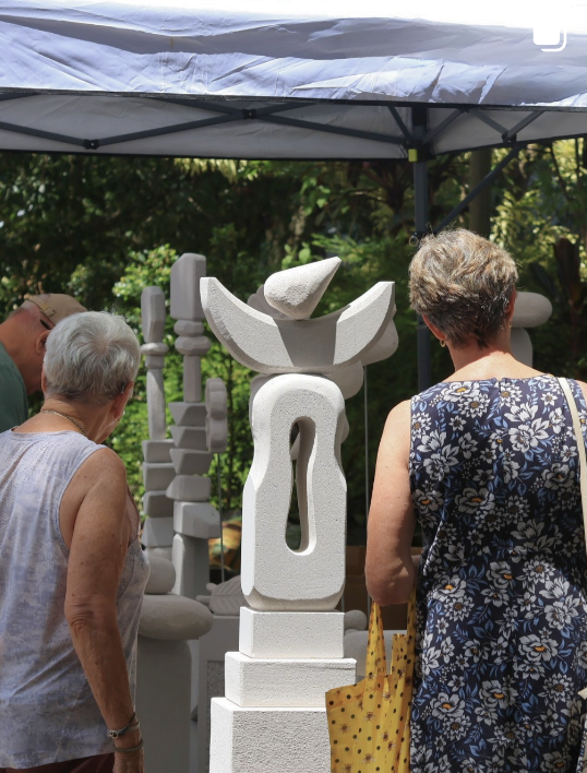 Visitors viewing a sculptor's work at the markets