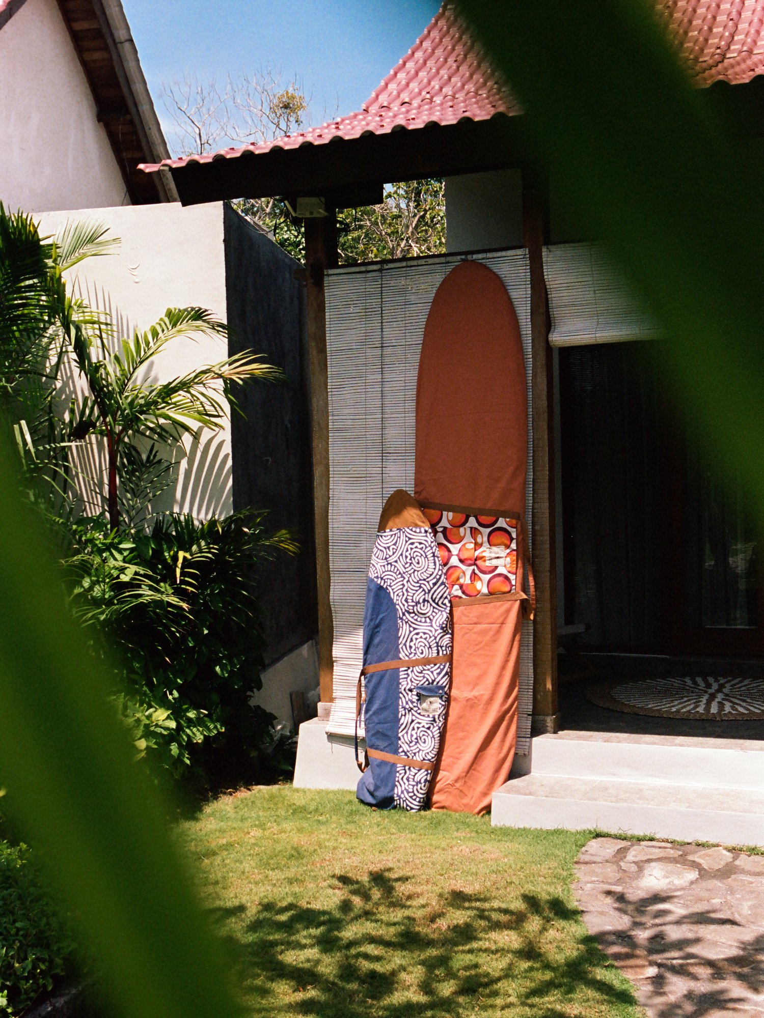 Two patterned Barefeet Surf board bags leaning outside a tropical villa