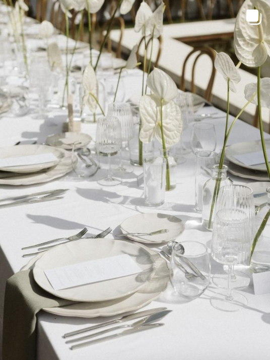 White wedding table setting with anthurium flowers and glassware