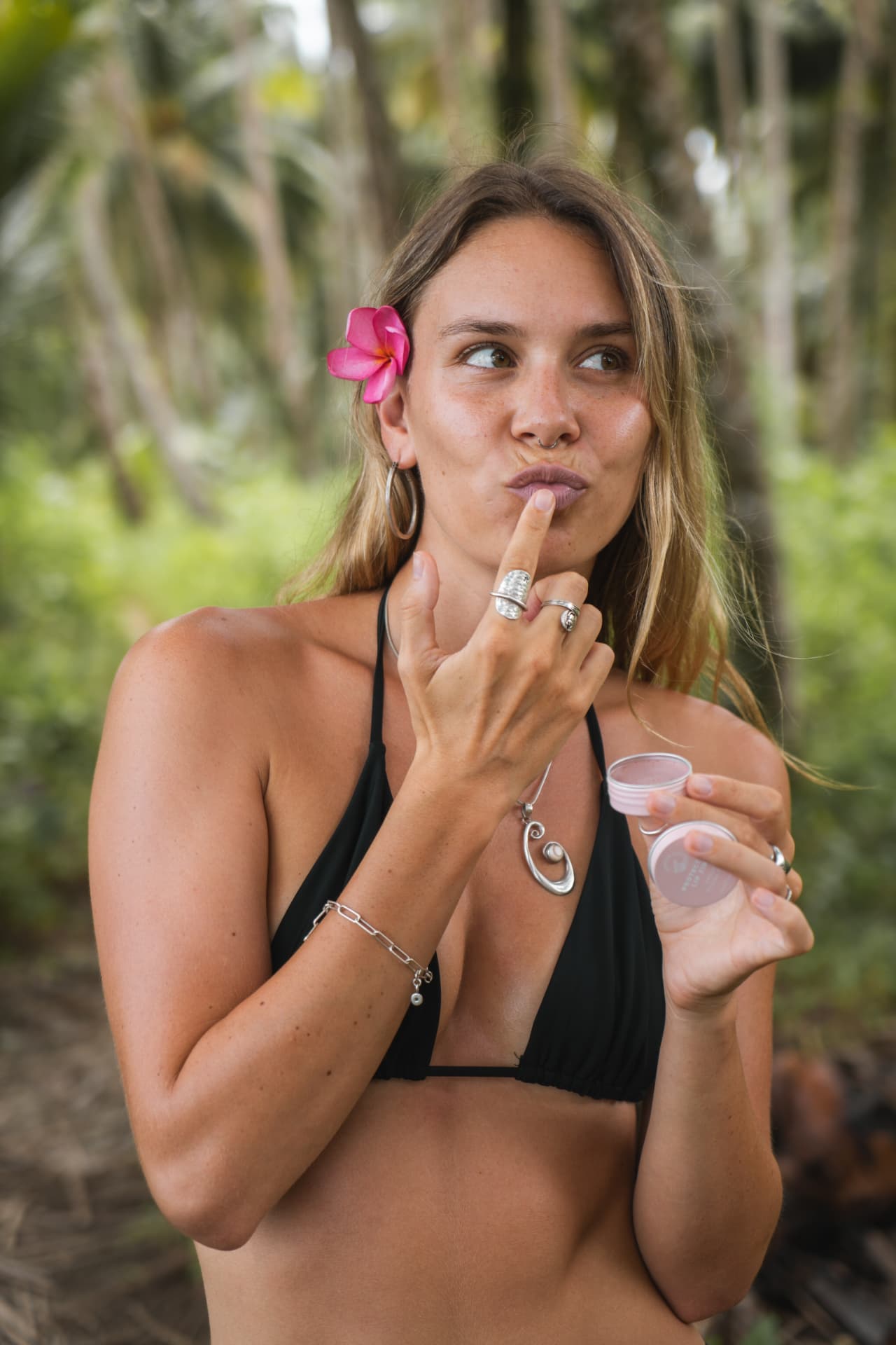 Woman applying sun care outdoors with a flower behind her ear