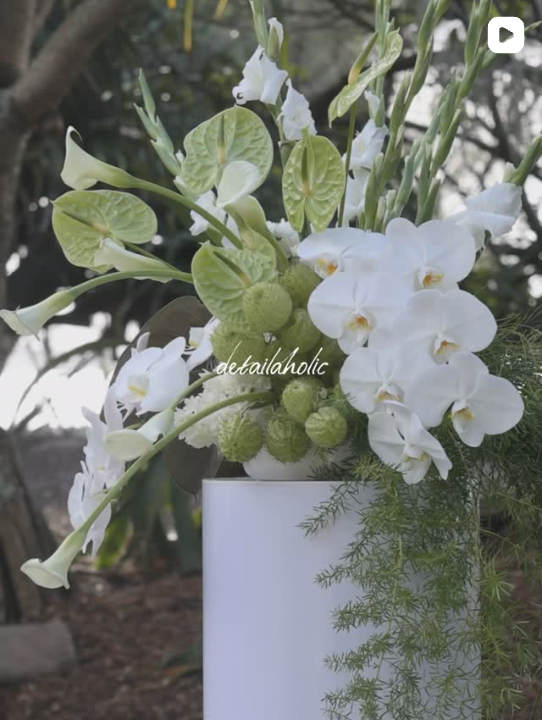 White and green floral arrangement styled on a white plinth