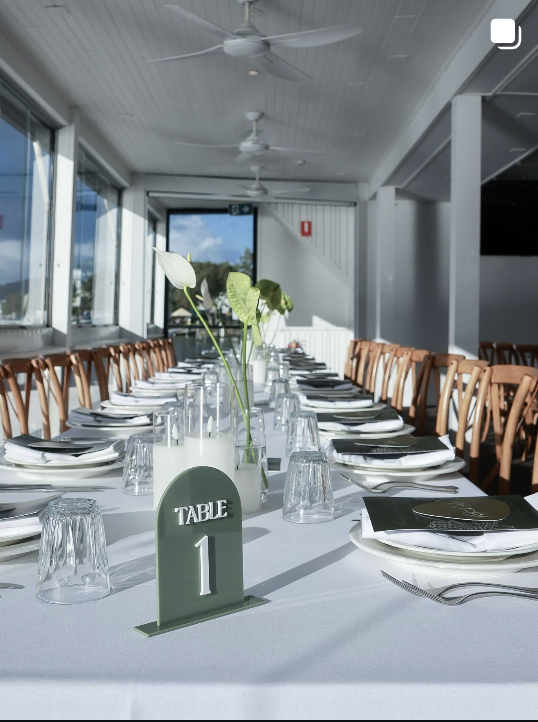 Reception tablescape with a green table number sign and timber chairs