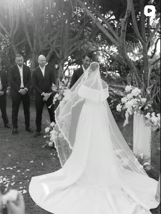 Black and white ceremony moment of a bride in a long veil facing the groom