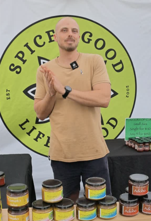 Market stallholder presenting a range of spice jars